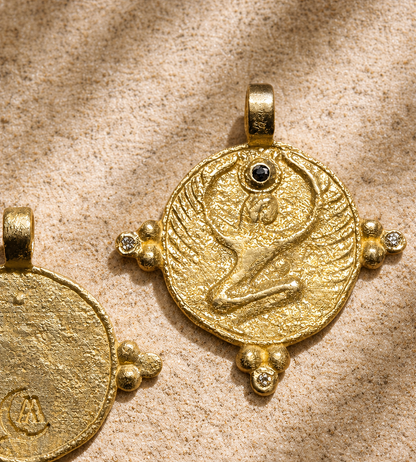 Gold Isis disc with black diamond crown stone on carved sandstone, talisman of protection