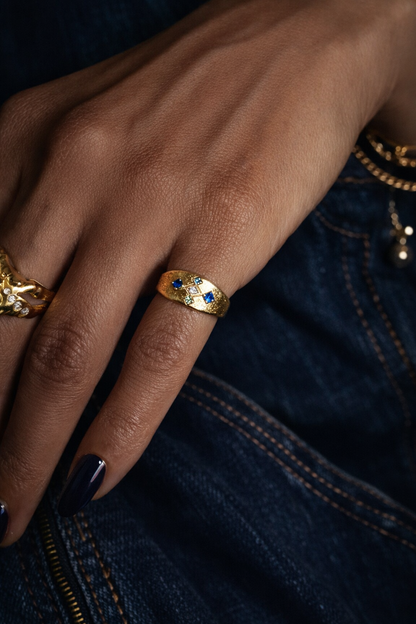 Gold Meskel with blue sapphires worn with denim, boho style rings stacked on hand