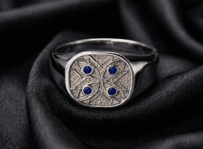 White gold signet with blue sapphire watchers resting on folded silk