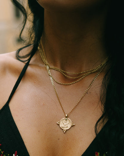 Model wearing the gold Isis pendant layered on fine chains, boho jewelry on black neckline