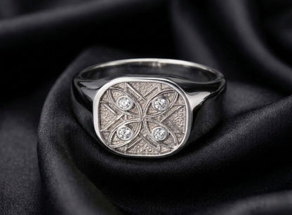 White gold signet with diamond watchers, eight point seal face on black satin