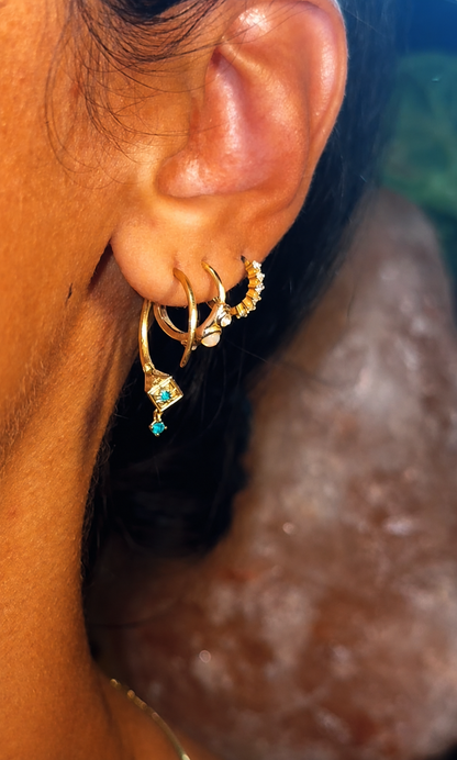 Gold Tuareg hoop with emerald drop worn in a curated ear stack, boho earrings styling