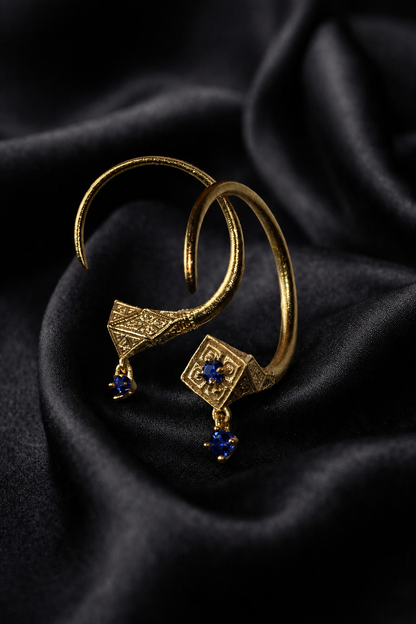 Gold Tuareg hoops with blue sapphire drops, engraved design faces on dark satin