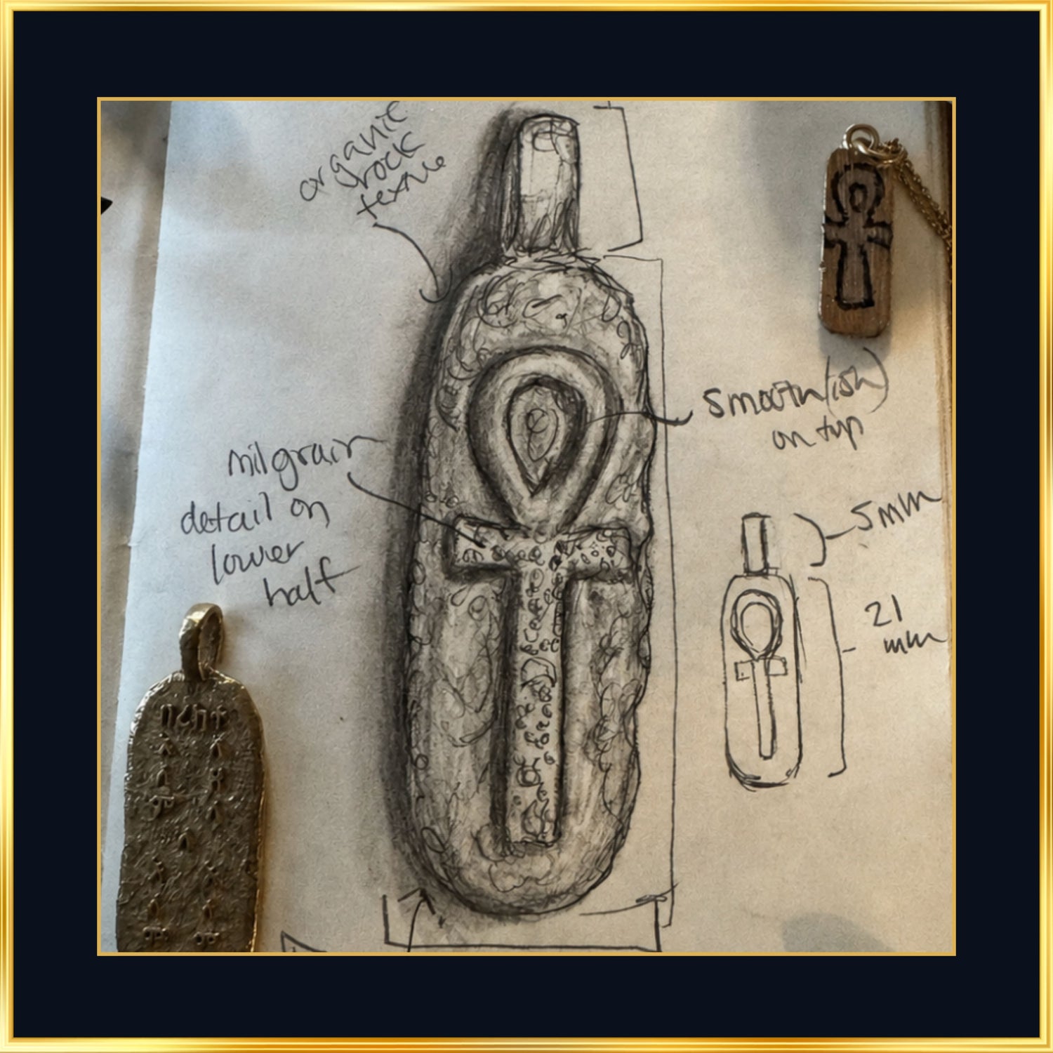 Ankh pendant sketch beside cast prototypes, ankh jewelry taking shape in the studio